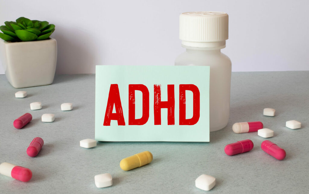 ADHD Medication | ADHD Testing in NYC | ADHD Behavior Therapy | ADHD Specialist NYC | 10018 | 10010 ADHD on notebook sheet against a medication bottle with pills laying around it. Struggling with your ADHD symptoms and unsure how to manage them? With medication management you can begin to reduce your symptoms soon.