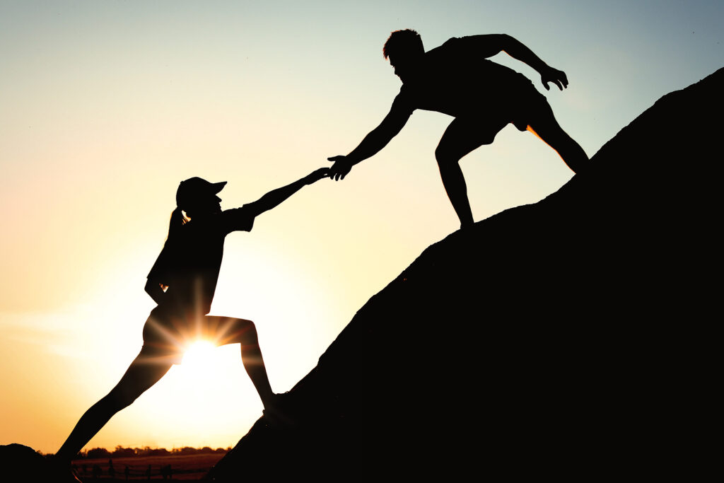 Hiker helping friend outdoors at sunset. Has ADHD management with medication not worked for you? The skilled therapists at ATTN Center in NYC understand and can support you in managing your ADHD without medication. Learn more here.