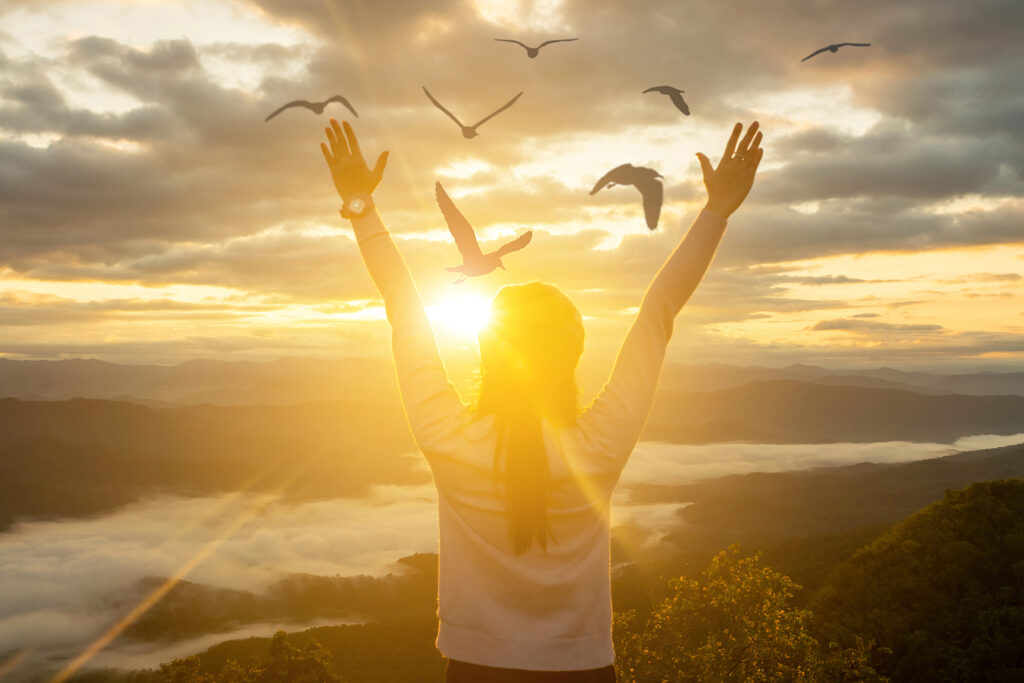 Woman Sunset | Online Therapy in NY | ADHD Specialist NYC | Brain mapping ADHD | 10018 | 10010 Photo of a woman holding her hands up during sunset with birds flying over her. Living with the symptoms of ADHD can be difficult. With ADHD treatment in NYC you can learn how to manage your symptoms easier. Learn more here.
