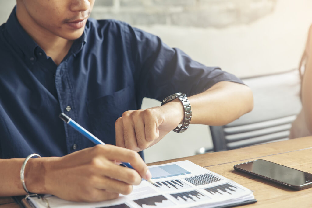 looking at watch | adhd therapist in nyc | adhd and ruminating thoughts | adhd therapist in new york, ny | 10003 | 10011 | 10012 A close up of a person looking at their watch as they write notes and work on papers. Learn how an ADHD therapist in NYC can offer support with overcoming ADHD and rumination in NYC today.